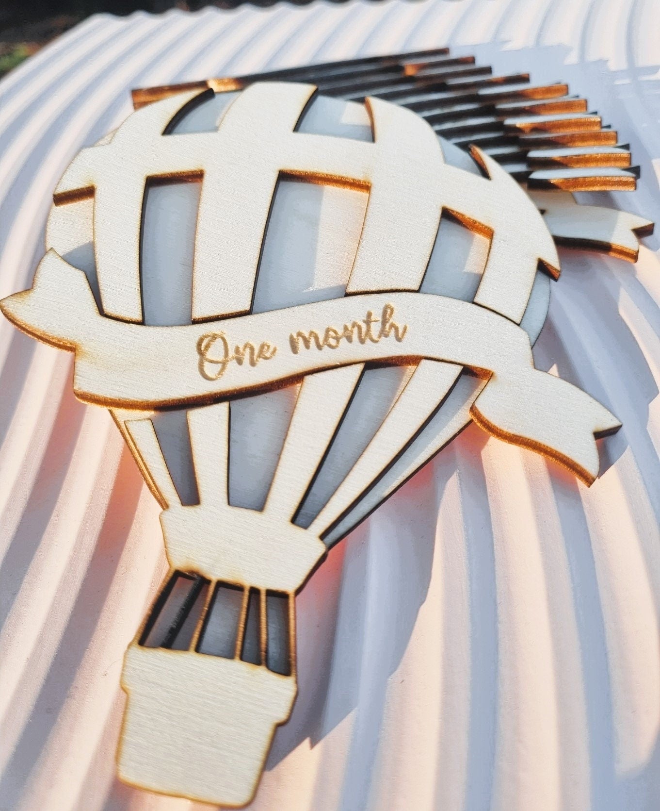 Baby Milestone photo prop set. The main piece is cut in the shape of a hot air balloon and each monthly milestone is engraved on a ribbon shaped piece of wood  that is interchangeable  in the centre of the balloon.