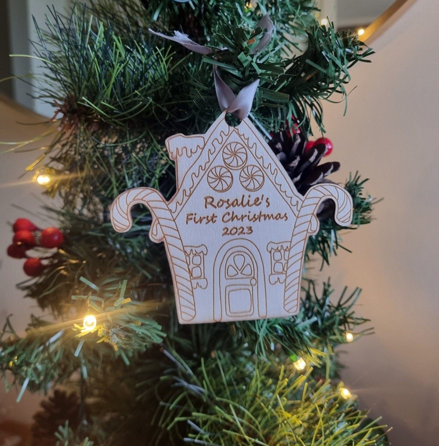 Personalised Christmas Tree Ornament made from poplar ply wood. It has been laser cut and engraved in the shape of a christmas gingerbread house and is hanging on a Christmas Tree.