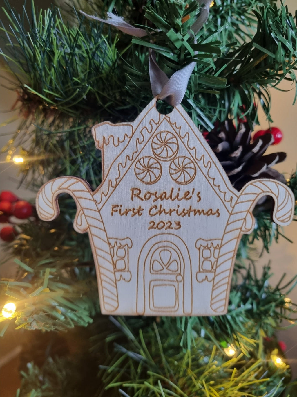 Personalised Christmas Tree Ornament made from poplar ply wood. It has been laser cut and engraved in the shape of a christmas gingerbread house and is hanging on a Christmas Tree.