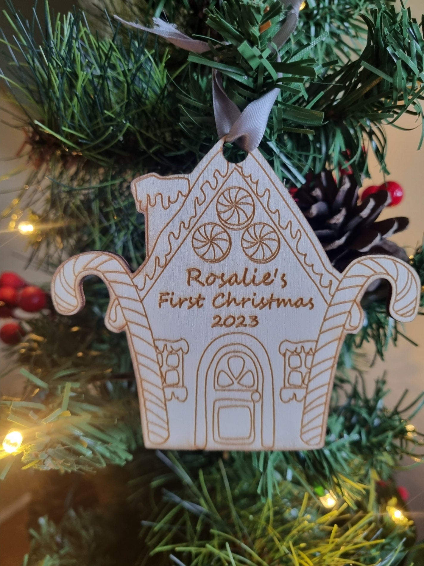 Personalised Christmas Tree Ornament made from poplar ply wood. It has been laser cut and engraved in the shape of a christmas gingerbread house and is hanging on a Christmas Tree.